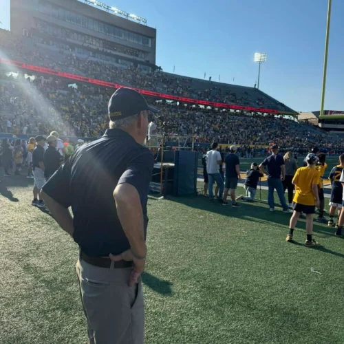 Jim standing on the field at the Mylan Puskar Stadium, enthusiastically observing the game