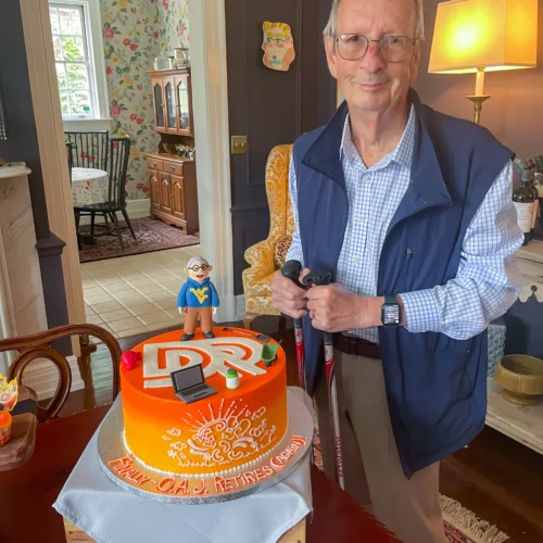 Jim posing next to a DR themed cake, featuring a fondant replica of himself
