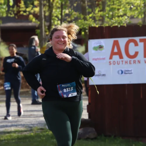 Alaina running with a race bib pinned to her shirt