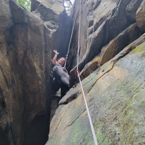 Hilary waving down from a rock climbing route
