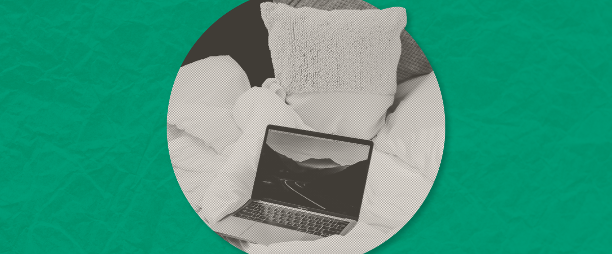Laptop open on a bed with pillows, displayed in a circular grayscale photo on a green background.