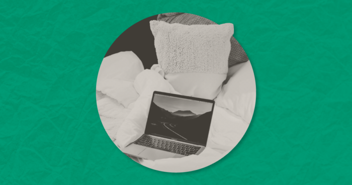 Laptop open on a bed with pillows, displayed in a circular grayscale photo on a green background.