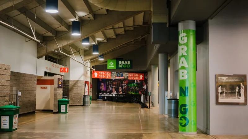 Navigational signage for GoMart's branded Grab N' Go location in the Charleston Civic Center. Colorful vinyl column wraps and hanging directional signage are visible in the shot - both prominently reflecting the GoMart brand.