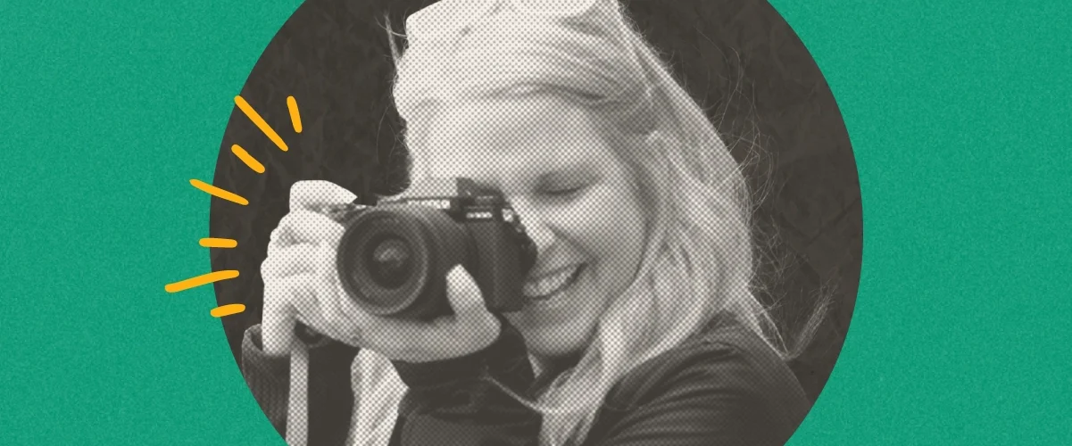 Woman with blonde hair smiling while holding a camera up to photograph, circular portrait on green background.