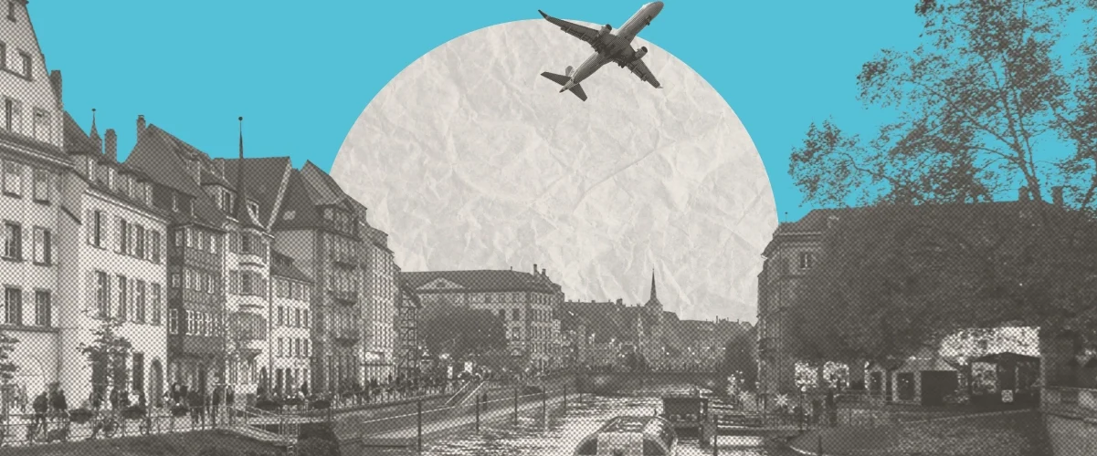 Black and white cityscape of a canal with historic buildings, a boat, and a plane flying overhead against a teal sky.
