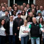 Leadership WV Class of 2025 group photo in front of a brick Welcome Center building, many wearing matching grey t-shirts with the Marshall University logo.