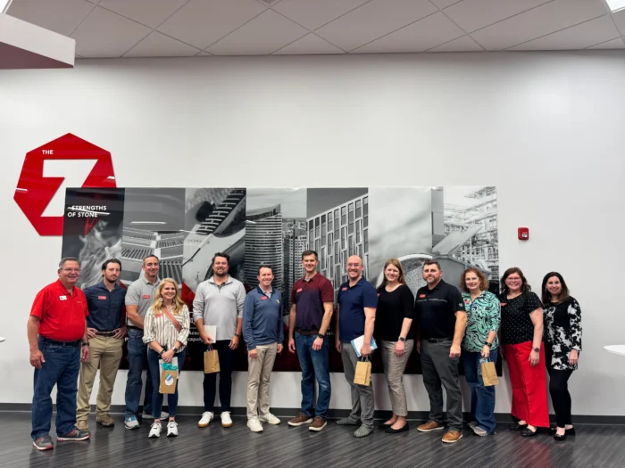 Group of professionals posing together indoors in front of a large black-and-white mural with a red "Z" logo.