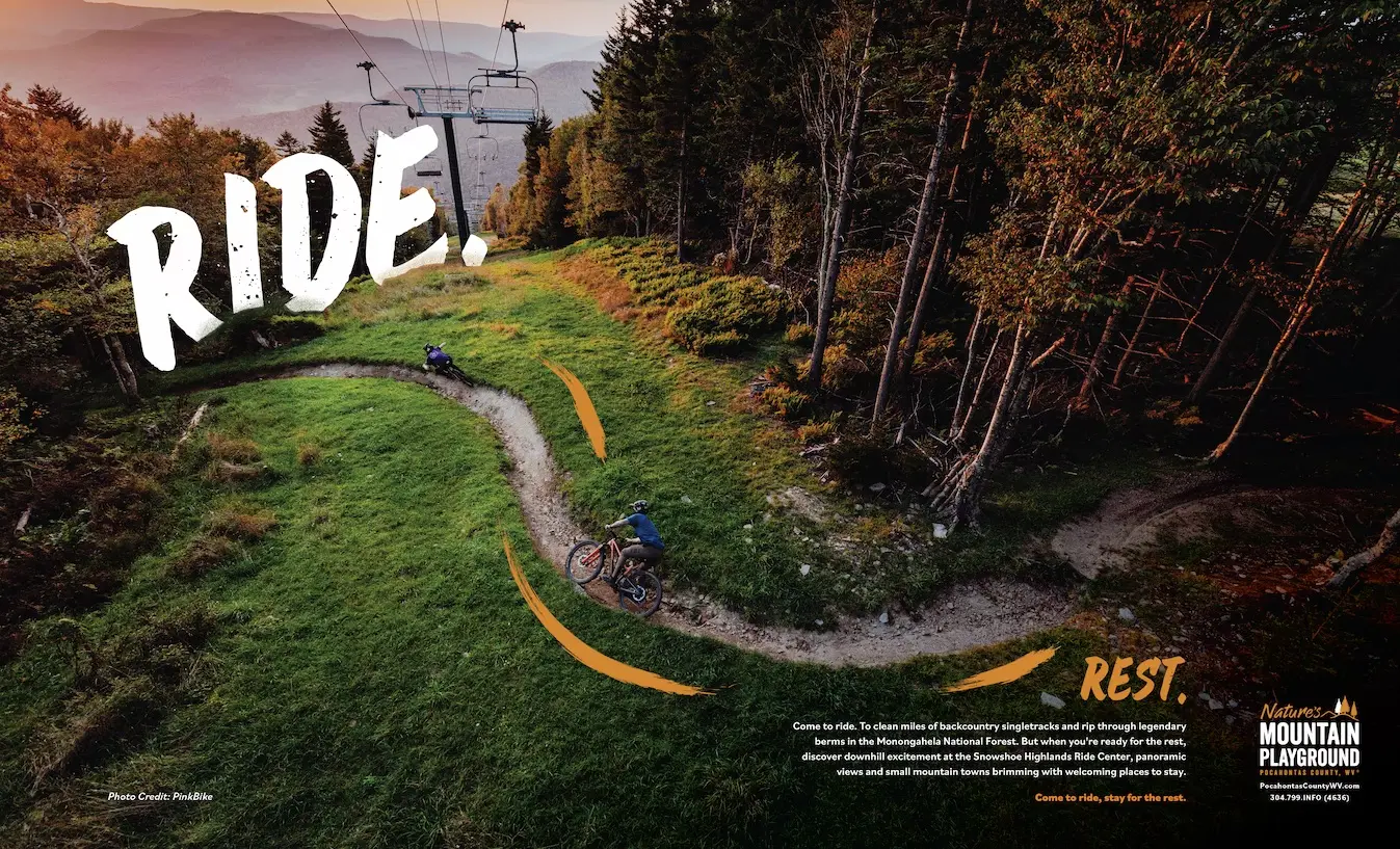 Aerial view of a winding mountain bike trail through green forest with 